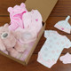 The Little Princess Baby Girl Gift Basket: A gift box containing baby items, including a pink bear plush toy, a pink hooded towel, a white onesie with floral patterns, and matching booties and hat. The box is placed on a wooden surface alongside a checkered blanket. The Little Princess Baby Girl Gift Basket: A gift box containing baby items, including a pink bear plush toy, a pink hooded towel, a white onesie with floral patterns, and matching booties and hat. The box is placed on a wooden surface alongside a checkered blanket.